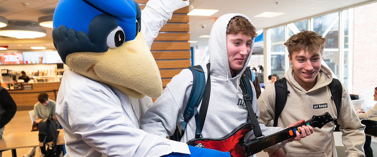 Two students play Guitar Hero with YoUDee during Geek Week