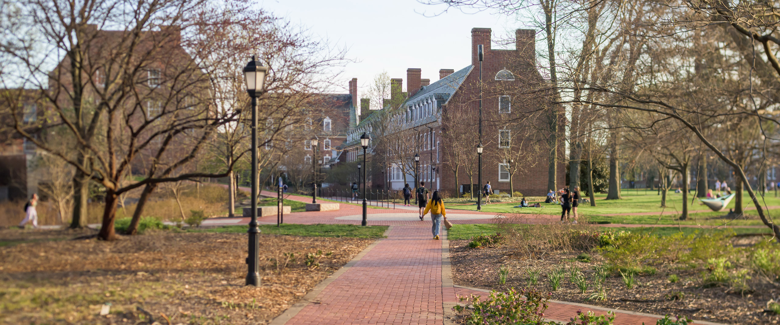 students walk along the pathways among central campus residence halls in early spring
