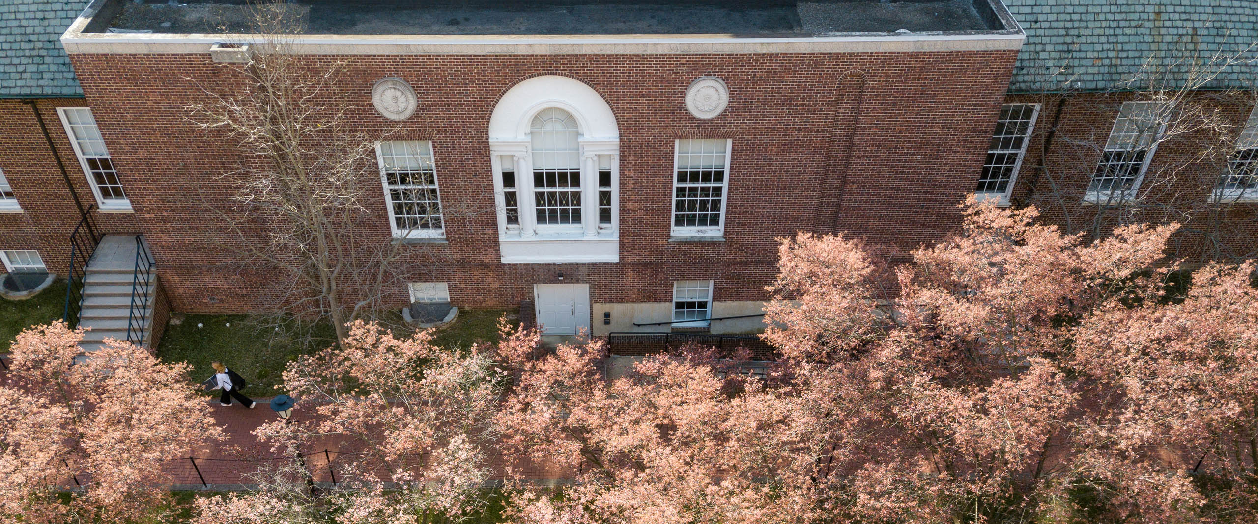 an aerial view of a UD building surrounded by blooming pink cherry blossom trees