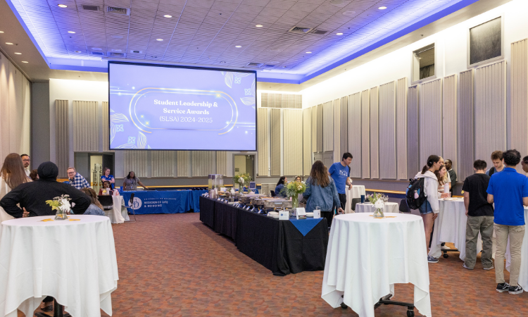 SLSA Award ceremony space with screen display of SLSA award logo and tables of food and students and staff sitting to each and talk