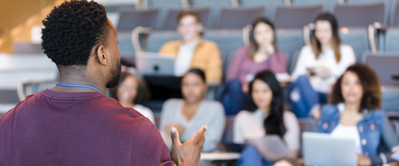a professor speaks in front of a classroom of students