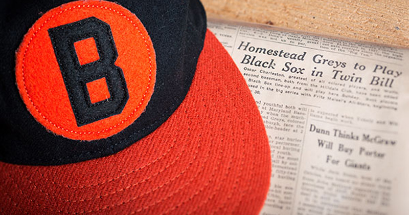Baltimore Black Sox hat over newspaper with headline
