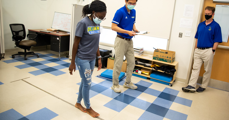 Joana Opung-Duah (left), a senior neuroscience and psychology major, runs through baseline concussion study protocol with Tsung-Yeh “Jacky” Chou, a doctoral student and certified athletic trainer from UD’s Athletic Training Research Lab. Chou is studying the effects of a concussion to neurological health in student athletes while Tom Buckley (right), an associate professor in the Department of Kinesiology and Applied Physiology, is studying prevention of future musculoskeletal injuries in athletes who’ve experienced concussion. This research is in partnership with UD Athletics.