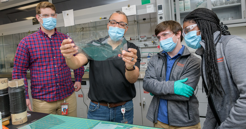Gerry Brown (second from the left), an R&D Technical Fellow, holds a Chemours fuel cell membrane as fellow Blue Hens and Chemours R&D engineers Robbie Loesch (left), Joey Pritchard (second from right) and Brittany Georges (right) look on. 