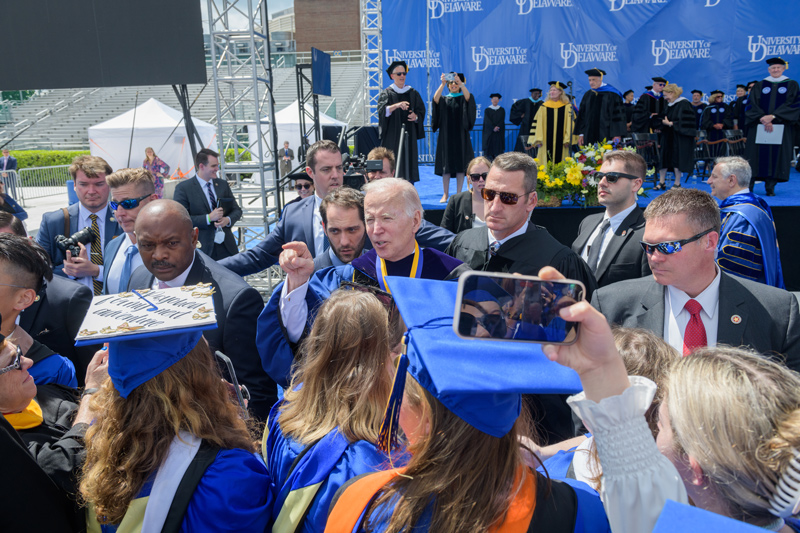 President Joe Biden, surrounded by members of the Secret Services, wades into a crowd of graduates and encourages them to face the world’s challenges. “You can make the difference,” he said.