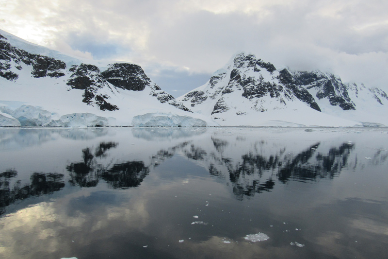 Mountains in Antarctica are reflected off the ocean water.