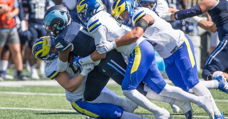 Delaware football players tackle a player from Rhode Island in 2022