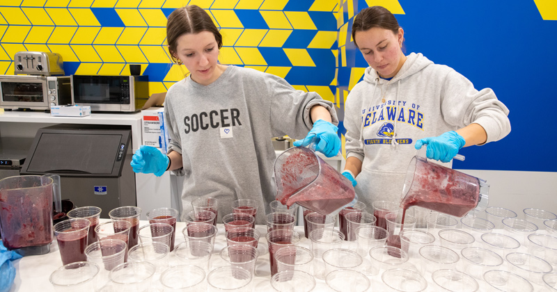 Two students in a kitchen preparing smoothies