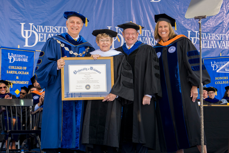  An honorary doctor of humane letters degree is presented to philanthropist and UD alumna Sally Ives Gore, mother of Delaware U.S. Sen. Chris Coons. Pictured are UD President Dennis Assanis, Ives Gore, Coons and Board Chair Terri L. Kelly.