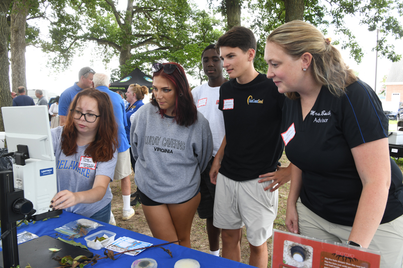 Brynn Bailey shows high school students how to use a microscope.