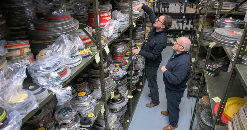 Kevin Martin (left), curator of audiovisual collections and digital initiatives at the Hagley Museum and Library, and Jim Culley, alumnus of UD’s MALS program, examine a portion of the thousands of sponsored films from Culley’s family film studio waiting to be preserved and digitized at Hagley.