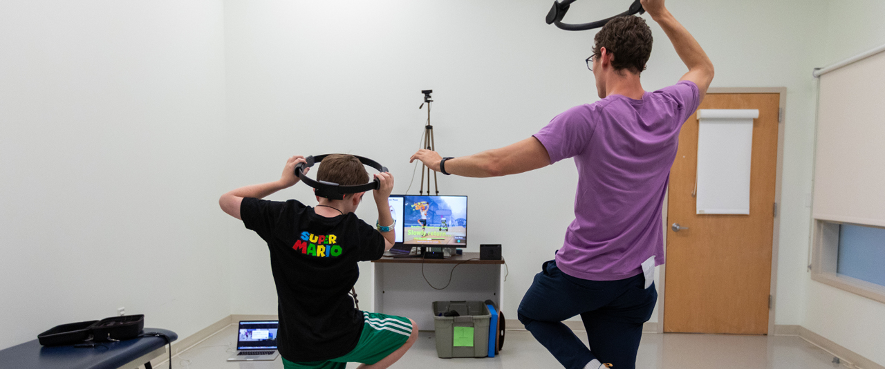 Reed, a 10-year-old boy with autism, gets his daily dose of exercise playing Ring Fit for Nintendo in Professor Physical Therapy Anjana Bhat’s Move 2 Learn Innovation Lab. Jacob Corey (right), a research assistant obtaining his doctorate in biomechanics and movement science, is working with Bhat on an exergaming study to determine whether Ring Fit can serve as an intervention that promotes motor skills, movement, and physical activity in individuals with autism, aged 7-21 years old.