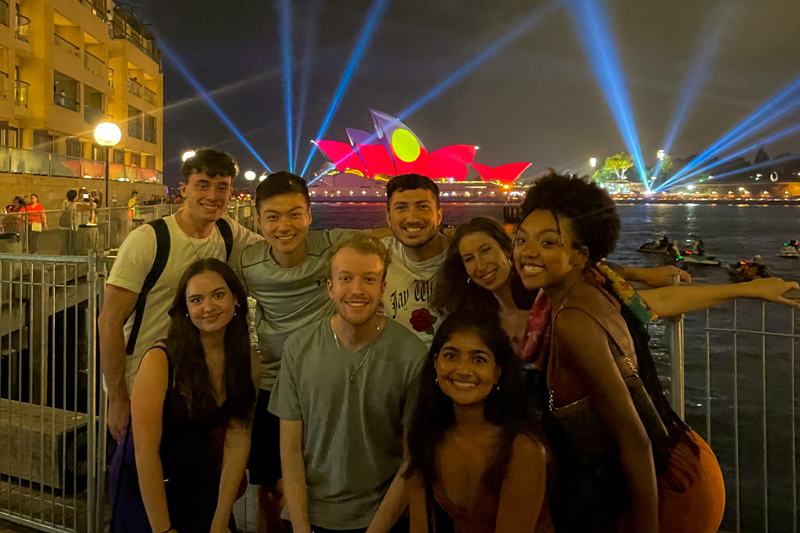 eight students standing by the colorful waterfront in Singapore at night