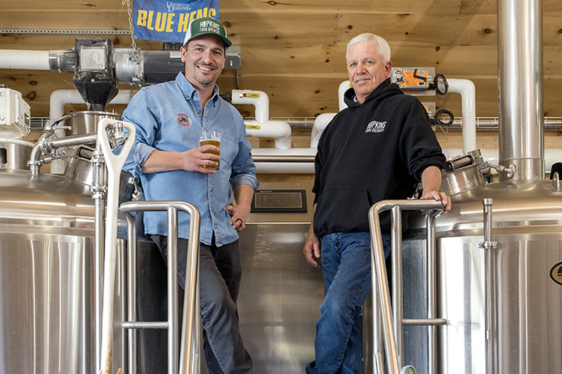 Father and son alumni David and Aaron Hopkins inside brewery farm.