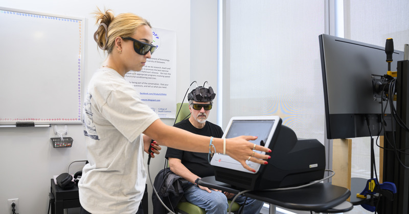 Sara Penuela Rodriguez (left), an interdisciplinary neuroscience doctoral student, administers infrared laser light therapy as part of a blinded study investigating its potential to address Parkinson’s symptoms by improving cellular metabolism and increasing blood flow.