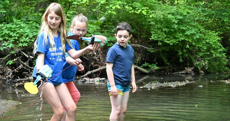 Elementary students test their aquatic robots in the creek behind University of Delaware’s The College School. 