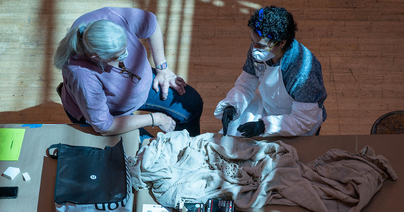 Two people sitting down, both with masks on