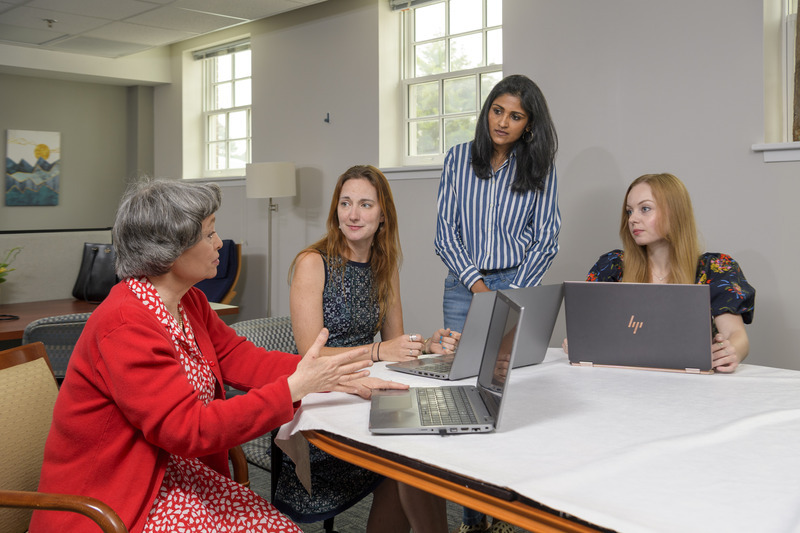 Four women sitting around a table with laptops actively holding a discussion