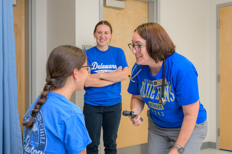 Nurse practitioner Heather Milea (right), conducts a sports physical at the Newark Charter School while athletic training graduate student Cassie Lee observes.