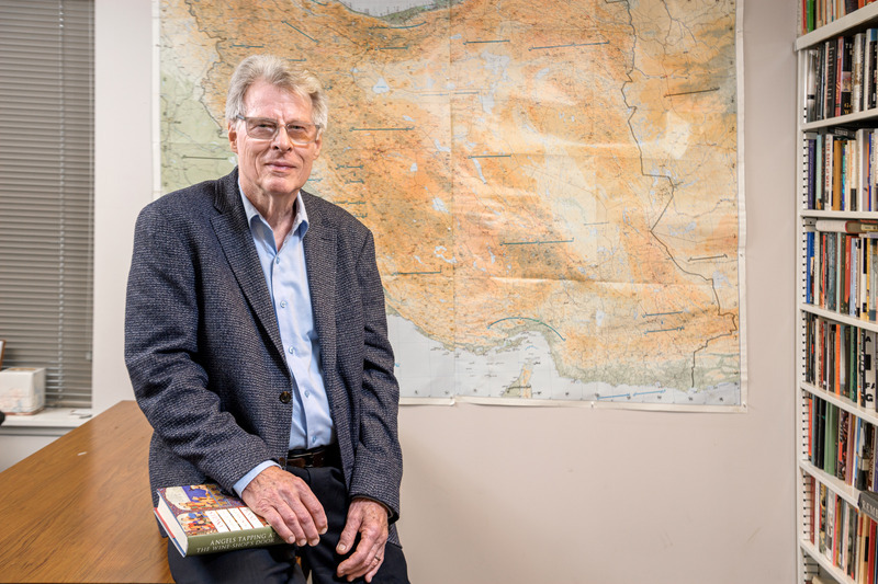 University of Delware Rudi Matthee posing in front of a 2D paper map of the world