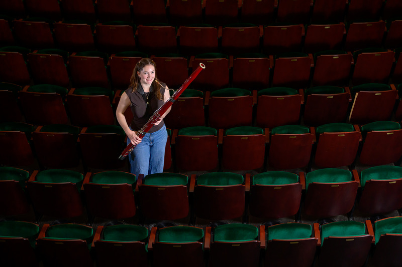 Julia McDonnell holding a bassoon in row of theater chairs