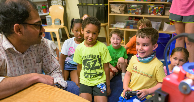 Cherukumilli talks with a student as he controls the microrobots. Starting with something familiar, such as a video game controller, helped the researchers explain the unfamiliar world of microrobotics to young children.