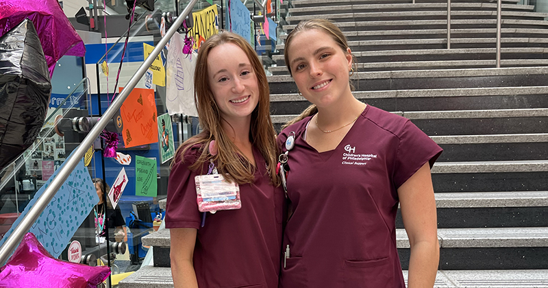Isabella Leonardo and Keira Allison on the steps of CHOP in scrubs