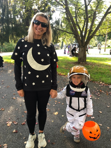 Alexis Milam standing next to child dressed up for Halloween