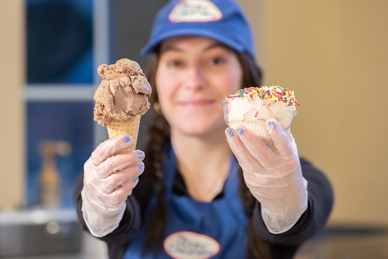 A student-employee serves ice cream at the UDairy Creamery