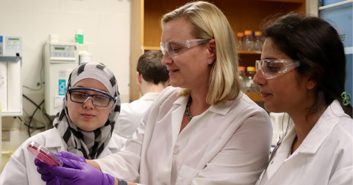 Three women in a food science lab working with a petri dish.