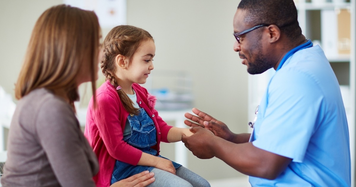 Check up at the doctor's office. A doctor meets with a little girl and her mother.