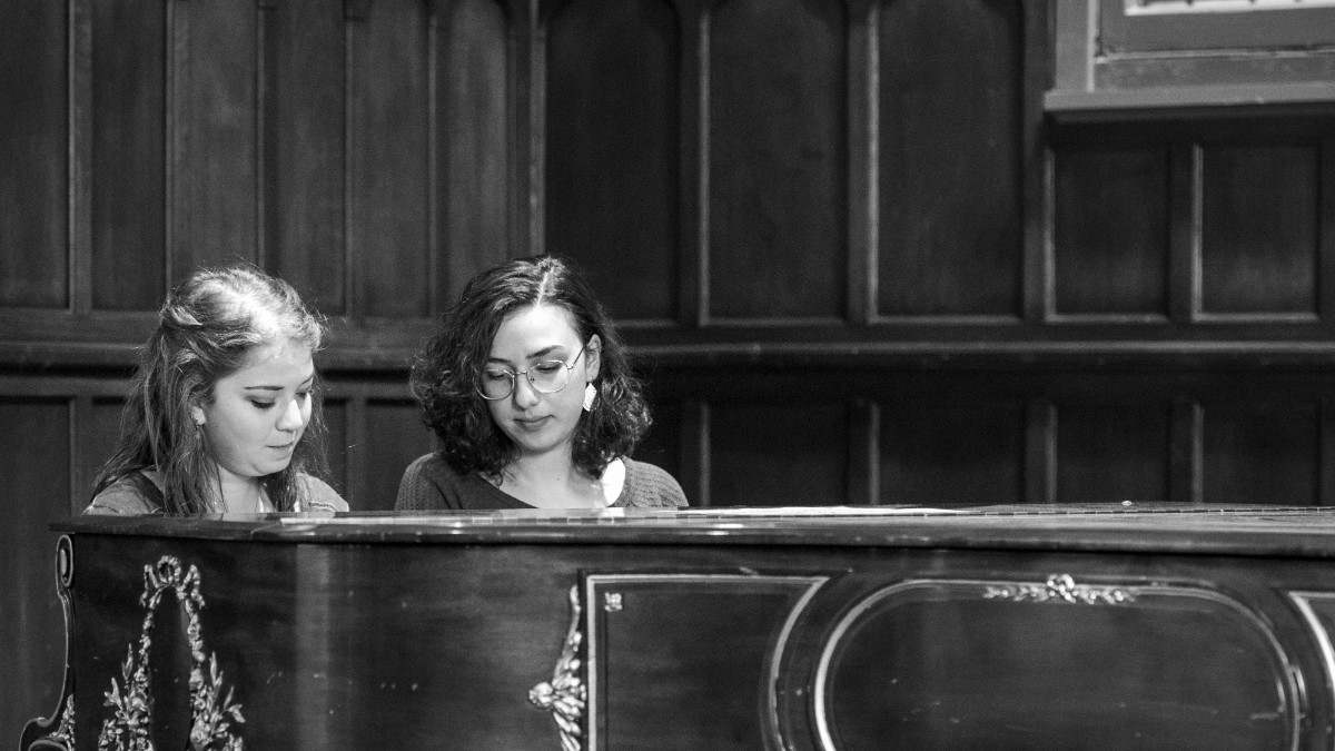 Two female students sitting at a piano
