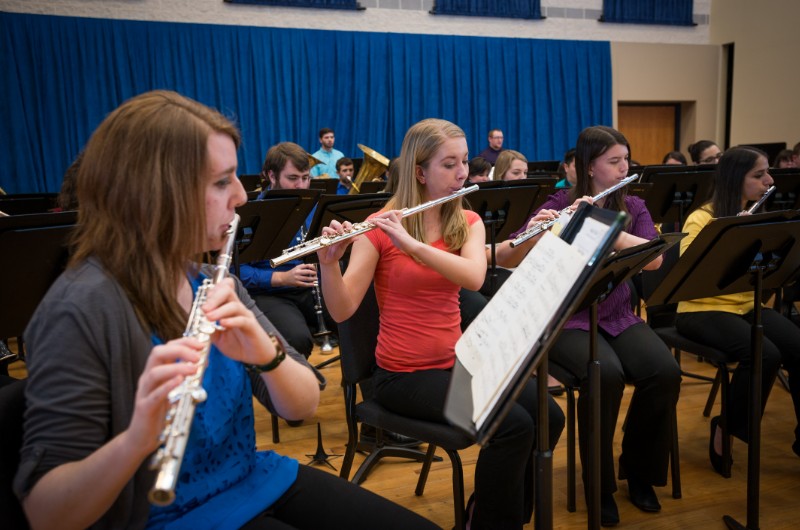 Students playing woodwind instruments in orchestra setting