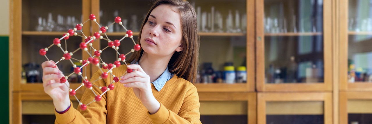 Young girl holding a science molecule made with wooden dowels