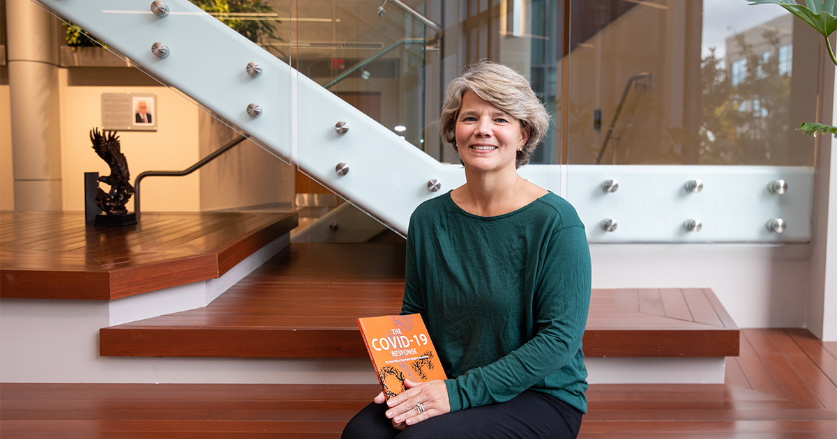 Jennifer Horney, professor and founding director of UD's Epidemiology Program poses in the STAR Building with her new book, "The COVID-19 Response: The Vital Role of the Public Health Professional."