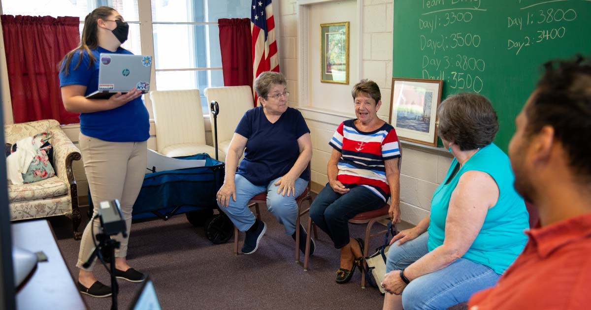 Two students interacting with three senior women