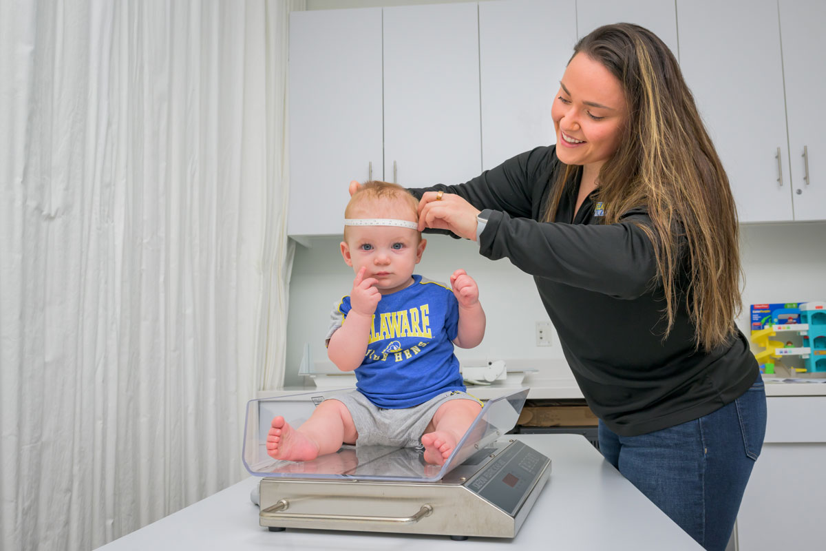Nutrition and Dietetics student measuring an infants head circumference while they sit on a scale