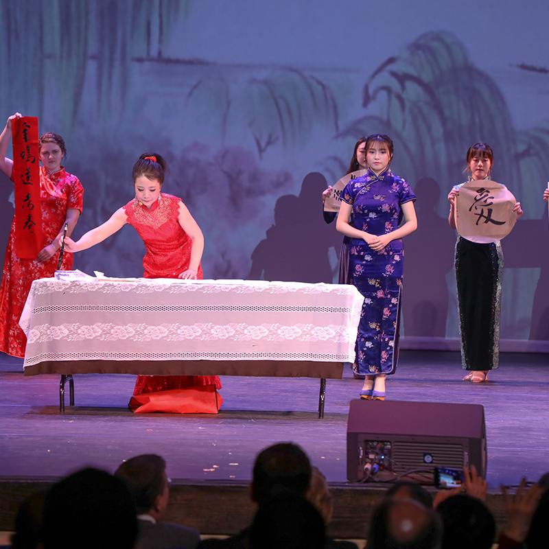 a photo of a woman singing Peking Opera and painting traditional Chinese calligraphy.