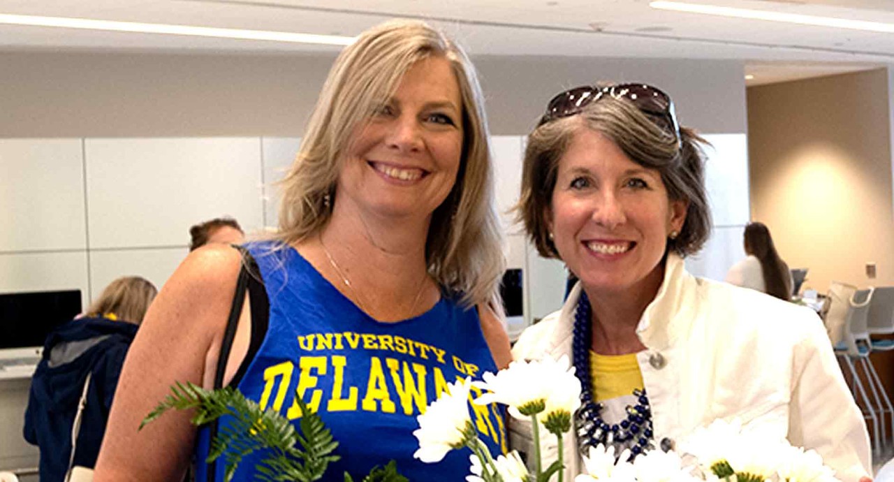 Two women smiling and holding flowers