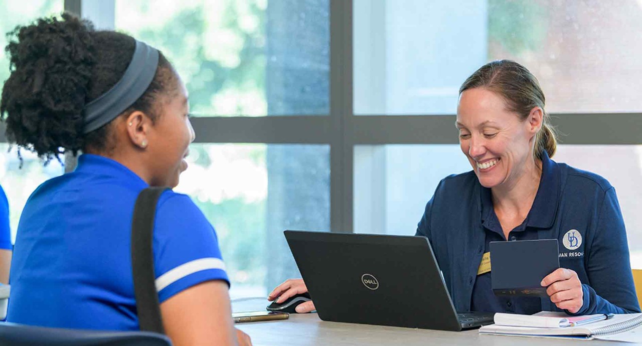 Woman sitting across from woman at laptop and smiling