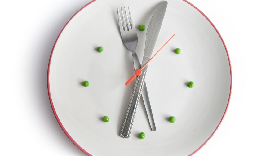 A clock made out of cutlery, a plate and peas.