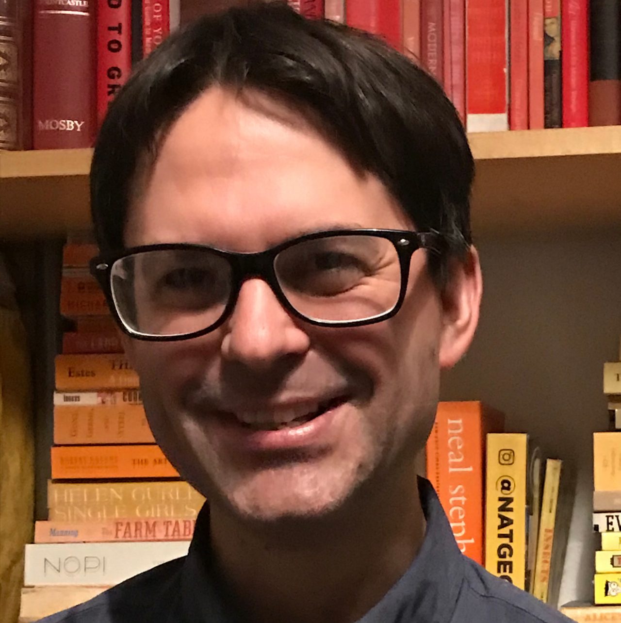 portrait of James Rising in front of bookshelf