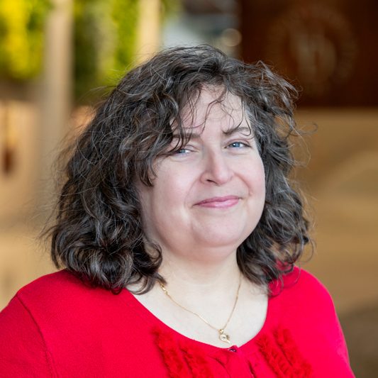 Headshot of Nicole Pekarek wearing a red shirt with a ruffle, taken in the STAR Tower lobby. 