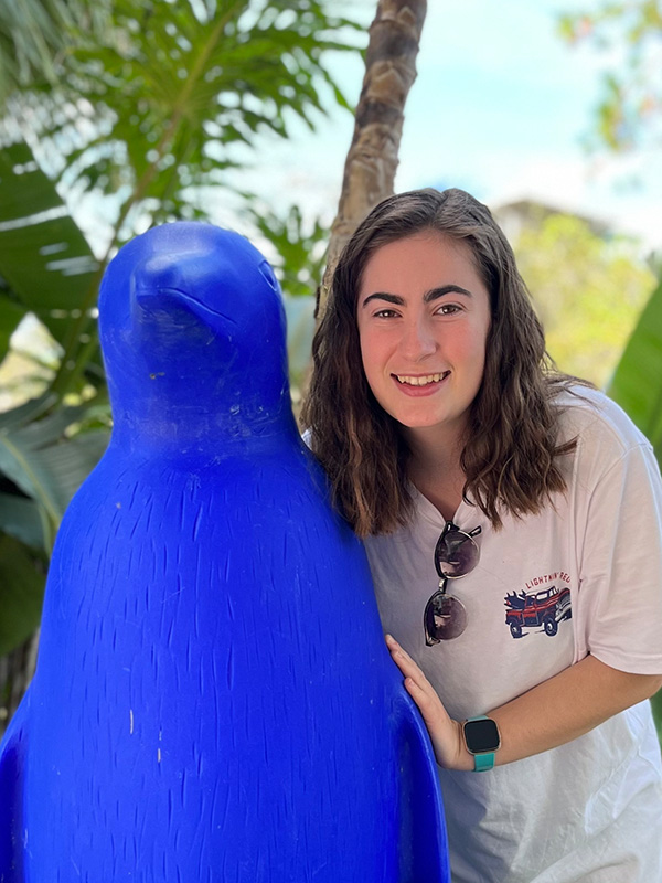 Young woman posing iwth blue penguin statue