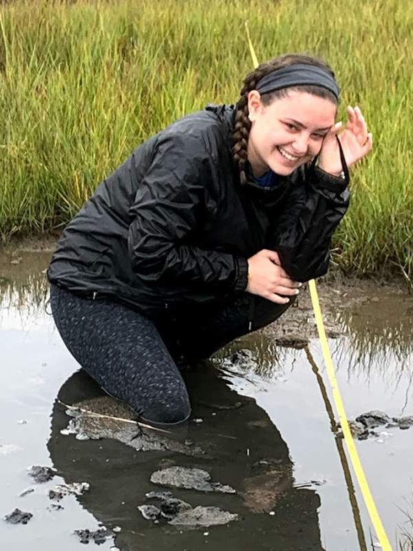 Young woman kneeling in shallow pond.