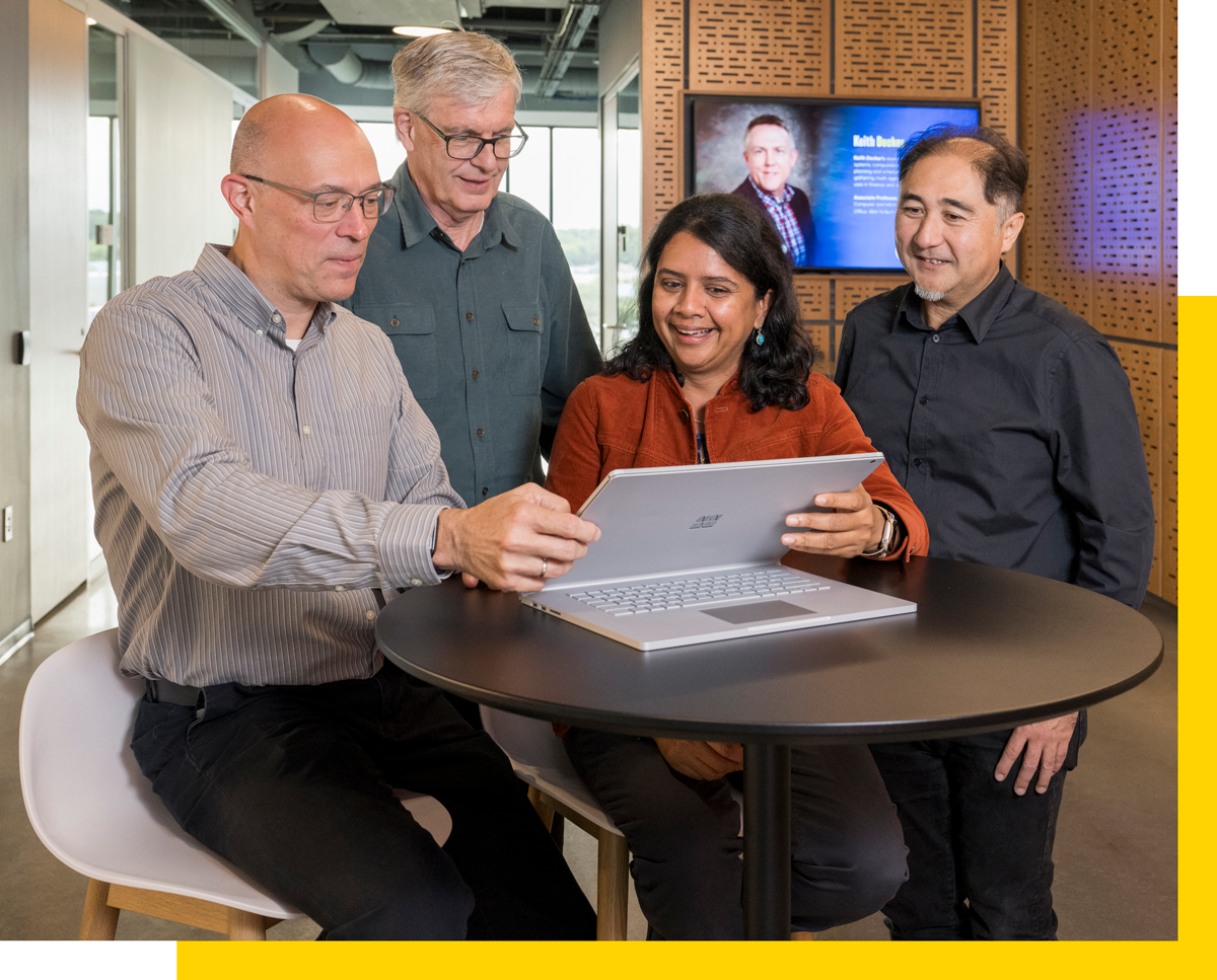 Various UD Faculty looking at a tablet and smiling.