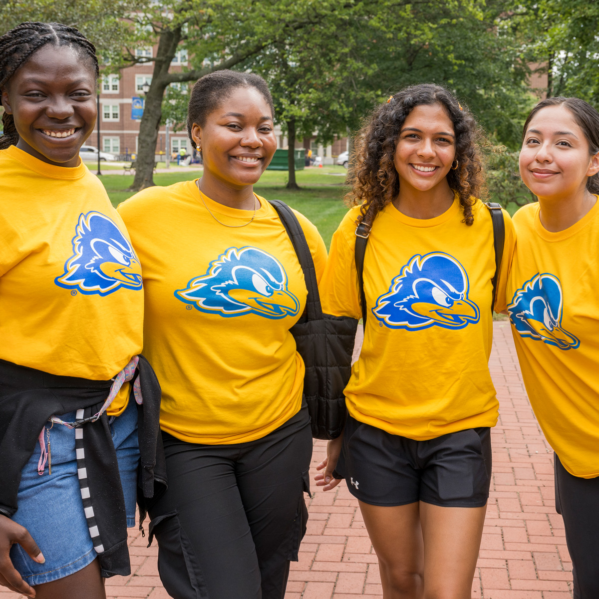 A group of students smiling during move-in with yellow shirts that feature YoUDee.