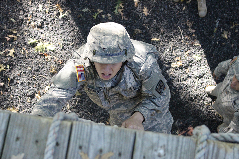 Army ROTC student scales a rope wall in training.