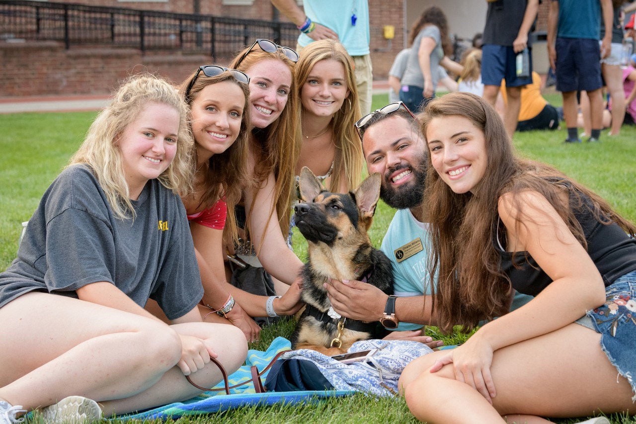 1743-Puppy_Playdate_On_The_Green-082618 Puppy rasiser students on a blanket outside.