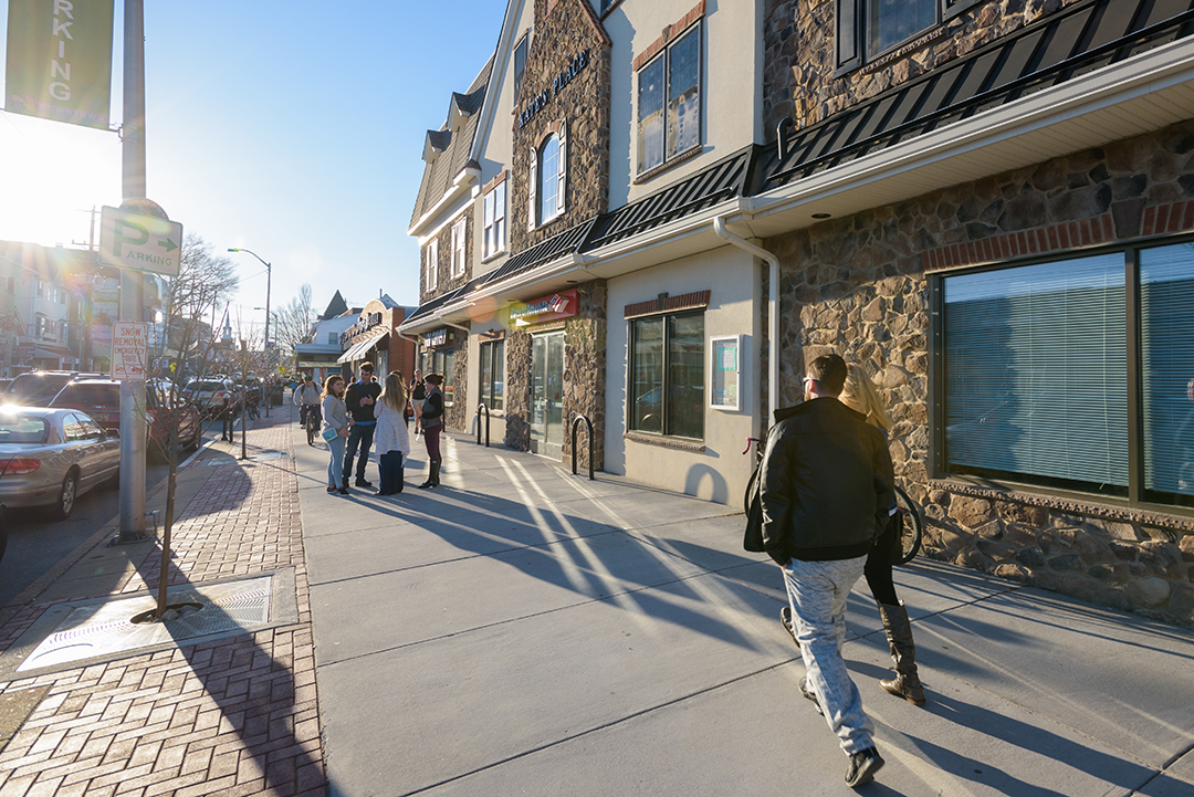 Students walk past storefronts and apartments on Main Street